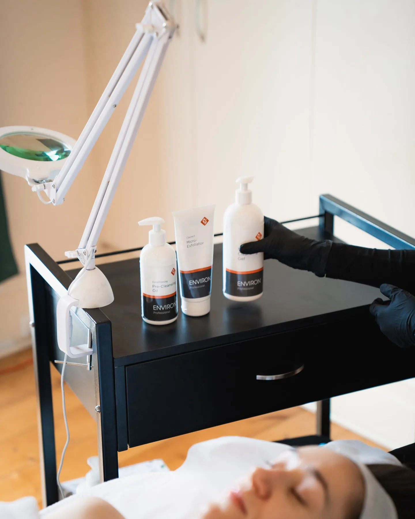 A clinician's gloved hand working alongside professional treatment products during a facial at Embrace